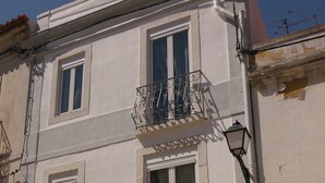 Un immeuble à plusieurs étages, doté d’une façade blanche, de nombreuses fenêtres et d’un balcon avec des rampes en métal.