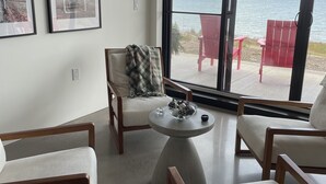 Ein modernes Wohnzimmer mit Meerblick, ausgestattet mit zwei Sesseln, einem Sofa und einem Couchtisch.