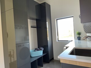 Una cocina moderna con lavadora y secadora integradas, una ventana con vistas y una pequeña planta en maceta sobre la encimera.