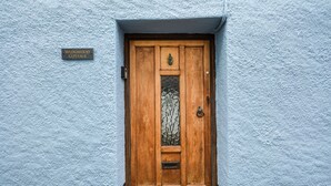 A wooden door with a glass panel and a metal handle, set in a textured blue wall. A sign above the door reads "WEDGWOOD COTTAGE." - Wedgwood Cottage - Sleeps 6 guests  in 3 bedrooms (Cawsand)