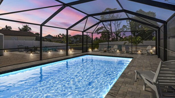 An outdoor swimming pool with a glass enclosure, surrounded by lounge chairs and a patio area. - CLEAN,Great Location,Dockage Available,HEATED Pool,3 Units, HUGE Back yard.Apt A (Englewood)