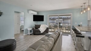 A modern living room with a sofa, a small table, and a TV mounted on the wall. - CLEAN,Great Location,Dockage Available,HEATED Pool,3 Units, HUGE Back yard.Apt A (Englewood)