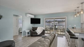 A modern living room with a sofa, a small table, and a TV mounted on the wall.