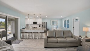 A modern living room with a sofa, a coffee table, and a dining area with a bar. - CLEAN,Great Location,Dockage Available,HEATED Pool,3 Units, HUGE Back yard.Apt A (Englewood)
