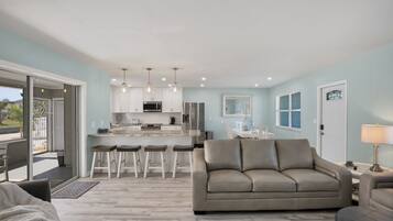 A modern living room with a sofa, a coffee table, and a dining area with a bar.