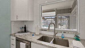 A kitchen with white cabinets, a marble countertop, a stainless steel sink, and a window with a view of a balcony. - CLEAN,Great Location,Dockage Available,HEATED Pool,3 Units, HUGE Back yard.Apt A (Englewood)
