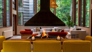 A modern living room with a fireplace, yellow chairs, and a sofa with cushions. - rakau lodge (Pucón)