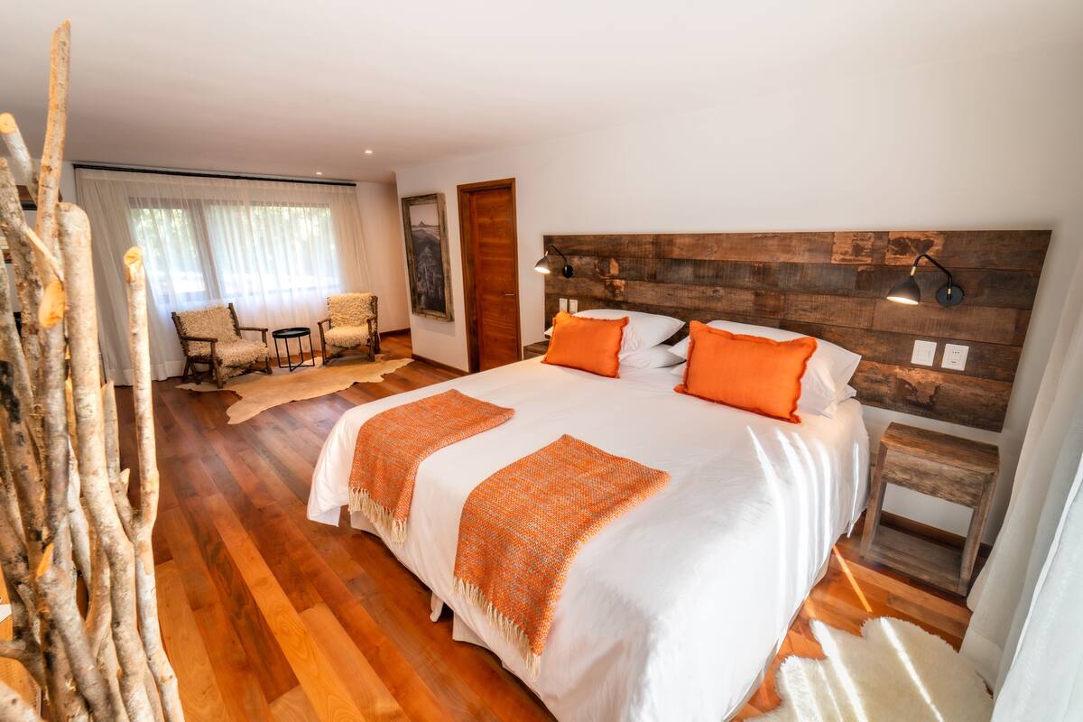 A bedroom with a large bed, wooden headboard, and a small bedside table.
