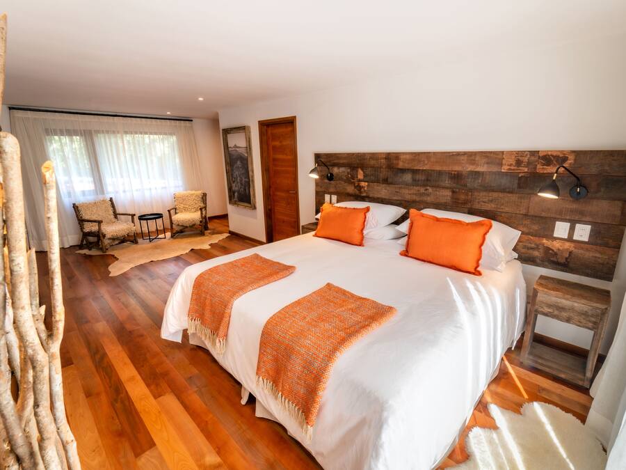 Quarto com cama grande, cabeceira de madeira e mesa de cabeceira pequena.