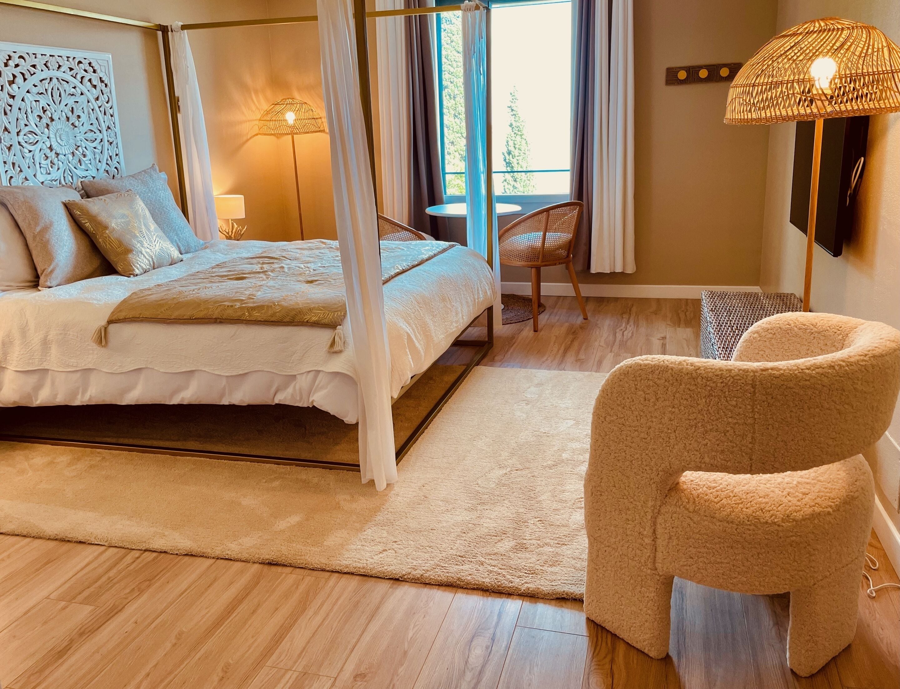 Un dormitorio con cama, una silla, una lámpara de pie y un ventanal con cortinas.