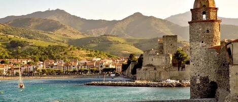 A coastal town with a historic tower, a stone wall, and a clear view of the sea.