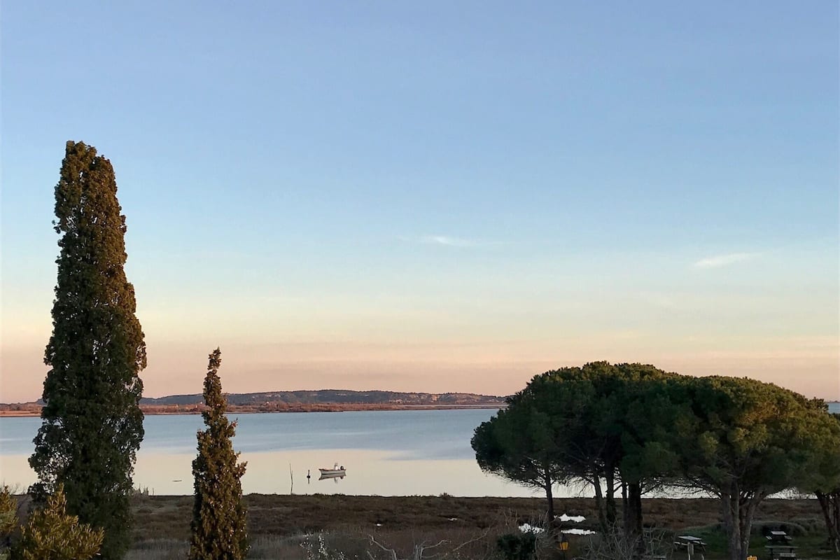 Paisagem costeira com céu claro, um corpo d'água calmo e um pequeno barco.