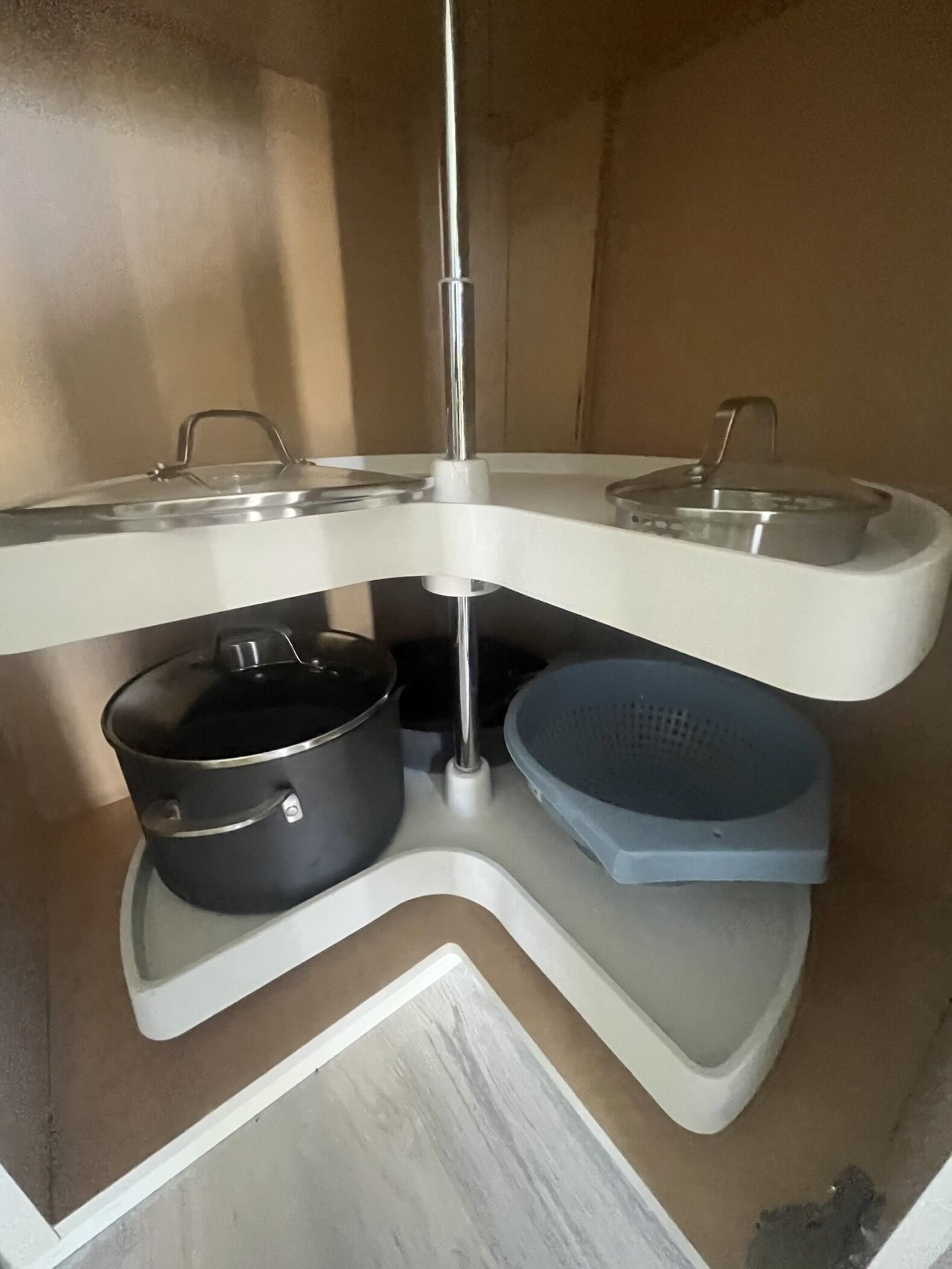 A kitchen with a white countertop, a black pot, and a blue colander.