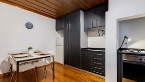Una cuina compacta amb armaris foscos, un refrigerador blanc i una estufa moderna.