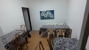 Un comedor con mesas y sillas, un cuadro en la pared y una puerta al fondo.