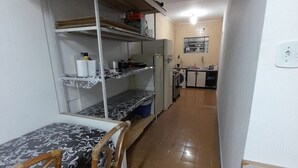 Una cocina compacta con electrodomésticos básicos, una zona de comedor con mesa y sillas, y una pequeña kitchenette con estantes.