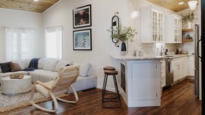A modern kitchen with white cabinets, a wooden ceiling, and a central island.