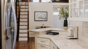 A kitchen with wooden ceiling, white cabinets, stainless steel appliances, and a coffee maker.