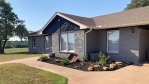 A two-story house with a brick exterior, large windows, and a well-maintained lawn. - Country Retreat north of Chandler (Tryon)