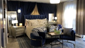 Una camera da letto con un letto grande, comodini, una scrivania, una sedia e una lampada a sospensione.