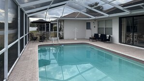 Une piscine intérieure couverte avec un toit en verre, un espace extérieur aménagé et une vue sur le paysage environnant.