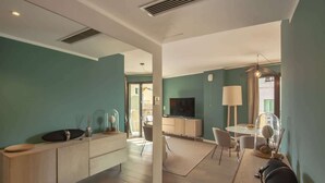 A modern living room with a kitchen area, a dining table, and a TV. - Casa Aliméa (Calenzana)