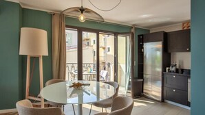 A modern kitchen with a large refrigerator, a dining table with chairs, and a view of the outside balcony. - Casa Aliméa (Calenzana)