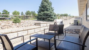 An outdoor patio with a stone wall, a large conifer tree, and a barbecue grill. - Two bedroom townhome, central to most popular destinations within Rapid City.   (Rapid City)