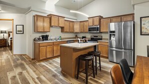 A modern kitchen with wooden cabinets, stainless steel appliances, and a central island with stools. - Two bedroom townhome, central to most popular destinations within Rapid City.   (Rapid City)