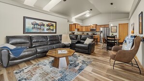A modern living room with a sectional sofa, a coffee table, and a dining area with a table and chairs. - Two bedroom townhome, central to most popular destinations within Rapid City.   (Rapid City)