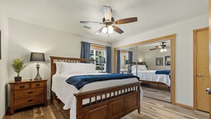 A bedroom with a wooden bed, a nightstand with a lamp, a ceiling fan, and a large mirror. - Two bedroom townhome, central to most popular destinations within Rapid City.   (Rapid City)