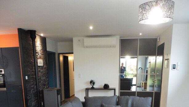 A modern living room with a grey sectional sofa, a wooden coffee table, and a large mirror.