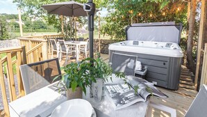 A hot tub, outdoor dining area, and a table set with plates and cutlery. - 4 bedroom accommodation in Llysfaen, near Colwyn Bay (Llysfaen, near Colwyn Bay)
