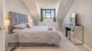 A bedroom with a large bed, a dresser, a mirror, and a window with curtains. - 4 bedroom accommodation in Llysfaen, near Colwyn Bay (Llysfaen, near Colwyn Bay)
