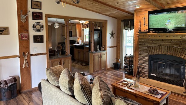 Een gezellig interieur van een chalet met een zithoek, keuken en open haard.