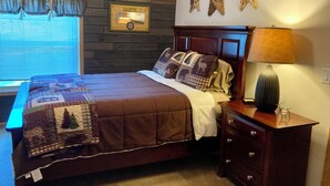 Een slaapkamer met een houten hoofdbord, een gewatteerde spreidekbed, een nachtkastje met een lamp en decoratieve sterren aan de muur.