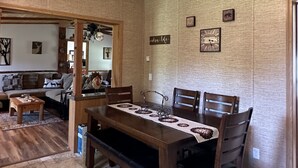 Een eetgedeelte met een houten tafel en stoelen, een bank en een hanglamp.