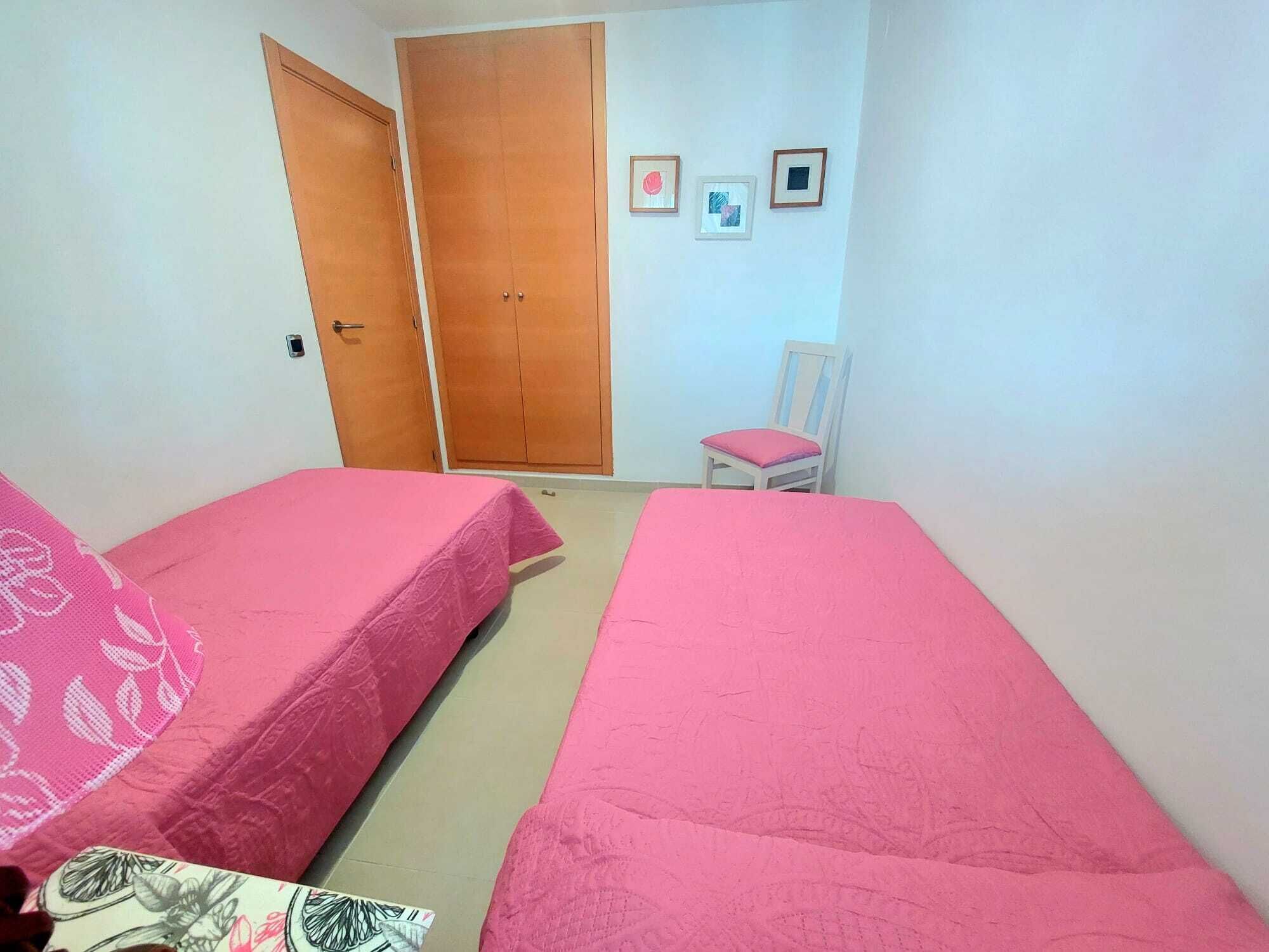 A room with two beds, a chair, and a wardrobe.