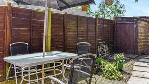 Un patio al aire libre con una mesa, sillas, una cerca de madera y plantas en macetas.