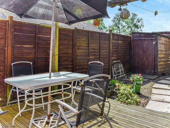Un patio al aire libre con una mesa, sillas, una cerca de madera y plantas en macetas.