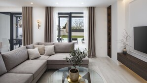 A modern living room with a sectional sofa, a glass coffee table, and a view of the outdoor patio. - Villa Bohemian Rhapsody with Pool (Marčana)