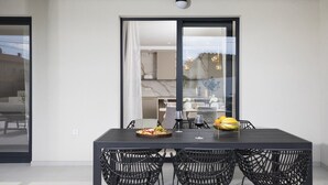 A modern dining area with a dark table and wicker chairs, a fruit bowl, and a wine glass on the table. - Villa Bohemian Rhapsody with Pool (Marčana)
