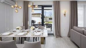A modern dining area with a table set for four, a sofa, and a view of the outdoors. - Villa Bohemian Rhapsody with Pool (Marčana)