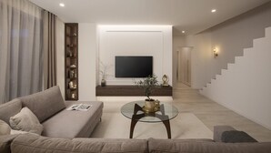 A modern living room with a sofa, a glass coffee table, a TV mounted on the wall, a staircase, and a decorative shelf. - Villa Bohemian Rhapsody with Pool (Marčana)