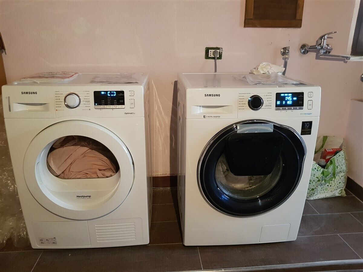 Two Samsung front-loading washing machines side by side on a tiled floor.