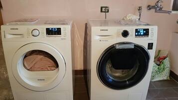 Two Samsung front-loading washing machines side by side on a tiled floor.