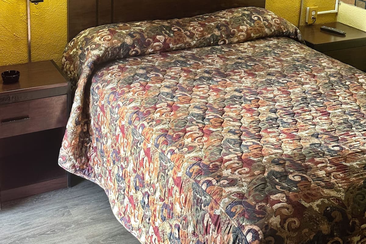 A hotel room with a large bed, two bedside lamps, and a wooden headboard.