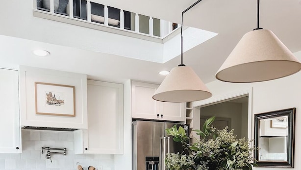 Cozinha moderna com bancada de madeira, eletrodomésticos de aço inoxidável e armários verde-claros.