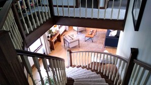 A staircase with white balusters leading to a living area with a sofa, coffee table, and a small rug.