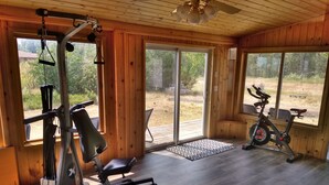 A gym with exercise equipment, large windows, and a wooden interior.